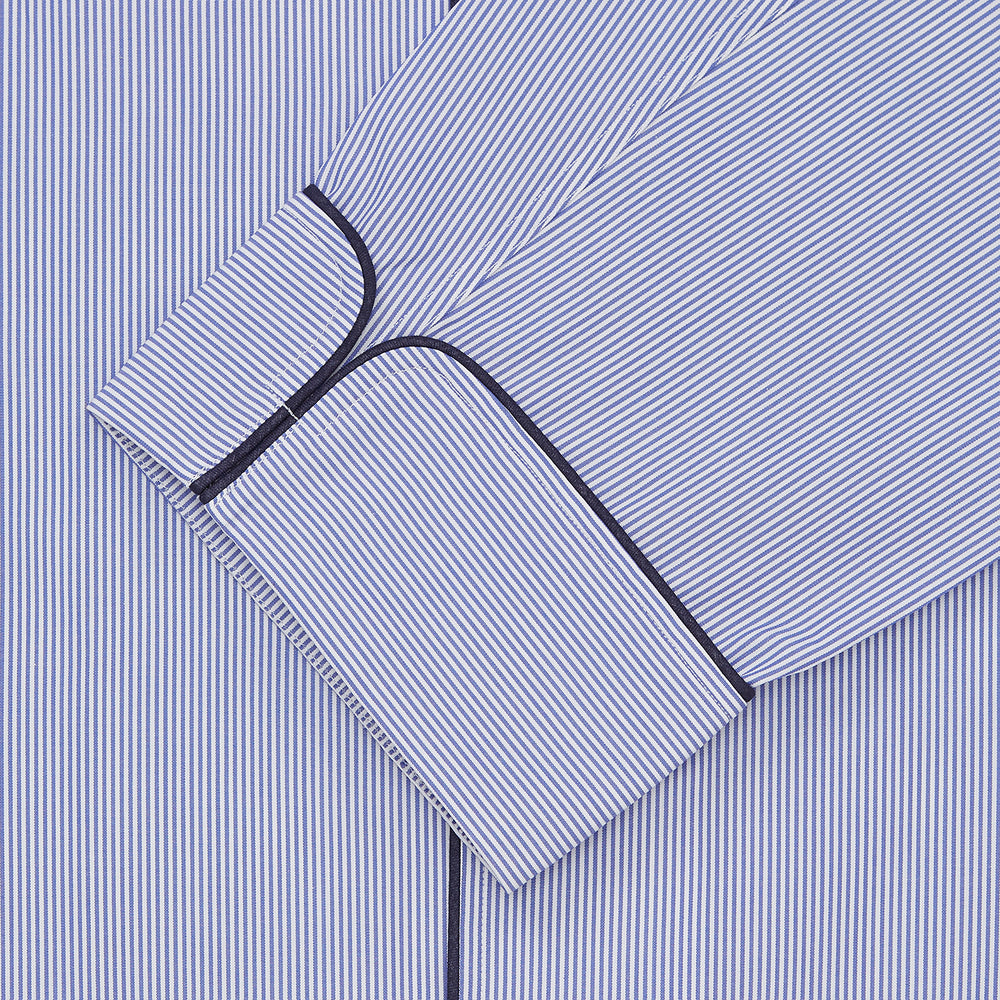 The Blue Fine Bengal Stripe Cotton Pyjama Set by Turnbull & Asser features a blue-and-white striped top with black piping, white buttons, and front pocket, displayed with a matching sleep mask—luxury sleepwear against a crisp white background.