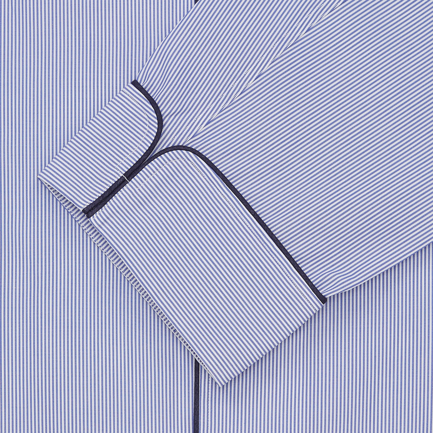 View 2 of product The Blue Fine Bengal Stripe Cotton Pyjama Set by Turnbull & Asser features a blue-and-white striped top with black piping, white buttons, and front pocket, displayed with a matching sleep mask—luxury sleepwear against a crisp white background.