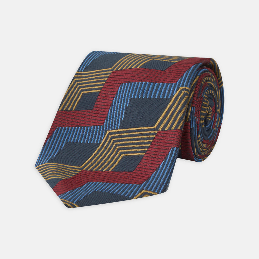 The Navy, Red and Gold Zig Zag Silk Tie by Turnbull & Asser features a geometric pattern of zigzag stripes on a dark background and is part of our limited-run collection.