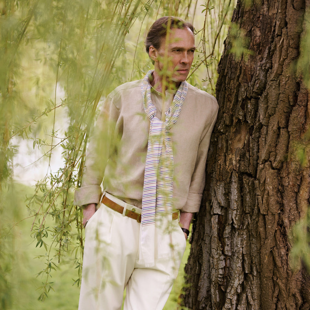 A man with a bald head and trimmed beard wears the Turnbull & Asser Beige Weekend Fit Linen Blake Shirt with stand collar and 1-button cuffs, standing calmly against a matching beige background.