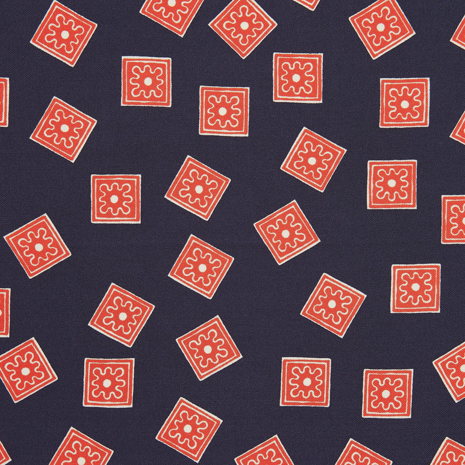 View 2 of product The Navy and Cherry Red Tiled Floral Silk Pocket Square by Turnbull & Asser features a blue background with red and white geometric floral patterns, a decorative border, and the brand's name in one corner.