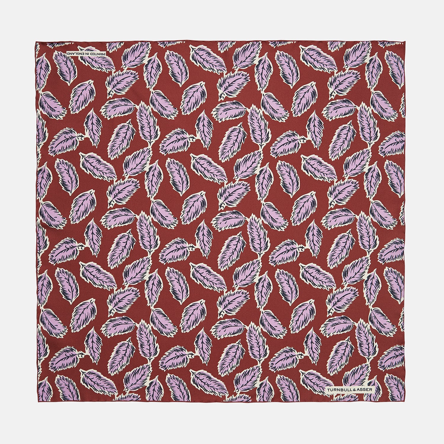 View 1 of product The Red Abstract Feather Print Silk Pocket Square by Turnbull & Asser features a dense purple and black feather pattern on red silk, accented with a discreet brand label—an elegant formal accessory.