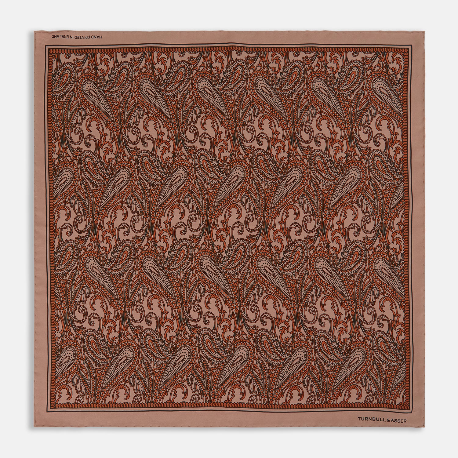 View 1 of product The Orange House Paisley Print Silk Pocket Square by Turnbull & Asser features a brown paisley design on a light brown silk background with a solid brown border and brand's logo printed in one corner.