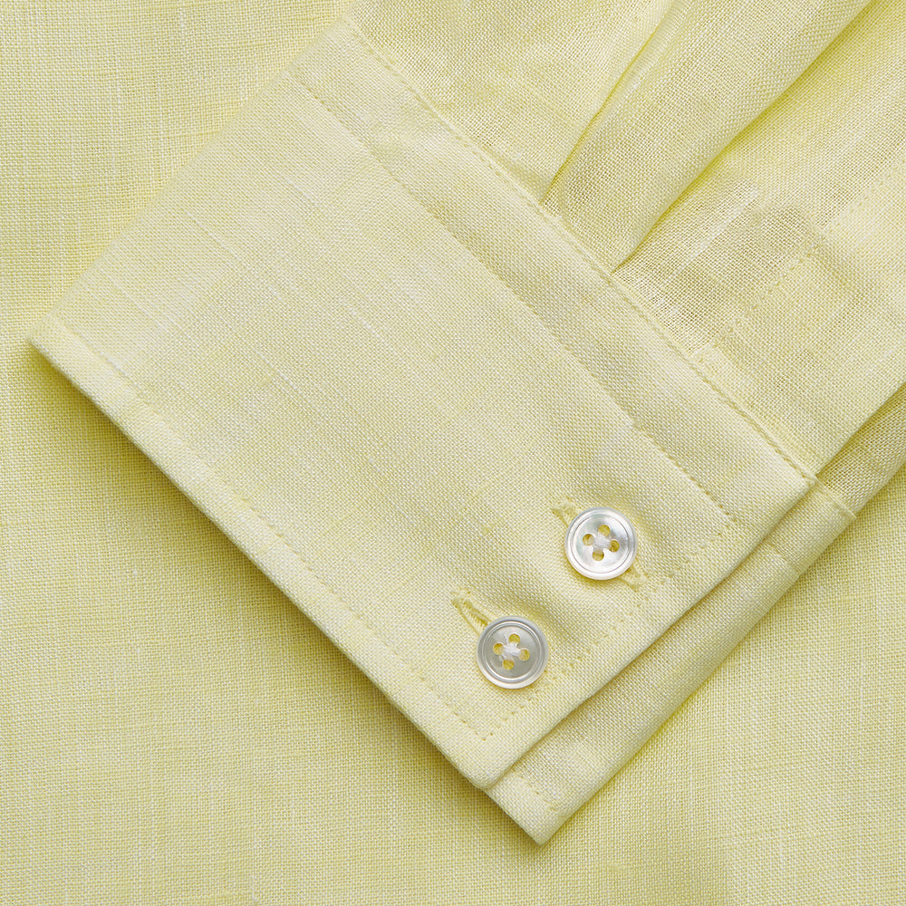 A man stands against a beige background, wearing the Turnbull & Asser Cream Tailored Fit Shelton Shirt with a Kent collar and black pants. He faces forward with a neutral expression, his arms relaxed by his sides.