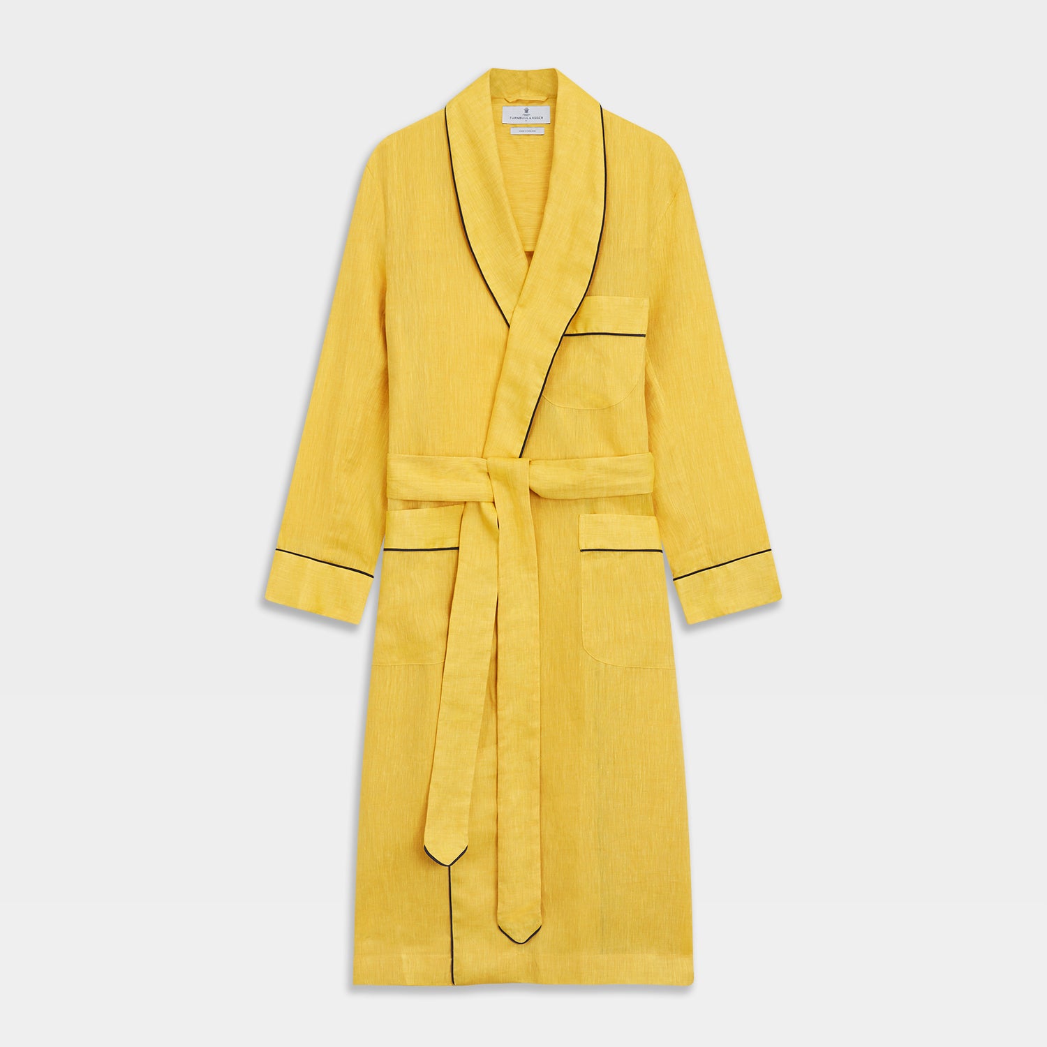 View 1 of product The Turnbull & Asser Ochre Linen Piped Gown features black piping on the collar, cuffs, and edges, a chest pocket, two front pockets, and a matching waist belt. Made with breathable linen for comfort, shown against a plain white background.
