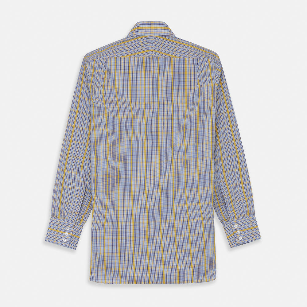 A man stands against a light background, wearing a Turnbull & Asser Yellow and Blue Fancy Check Regular Fit Shirt with T&A Collar, a patterned tie, dark dress pants, and black shoes. He faces forward with hands in pockets and a neutral expression.