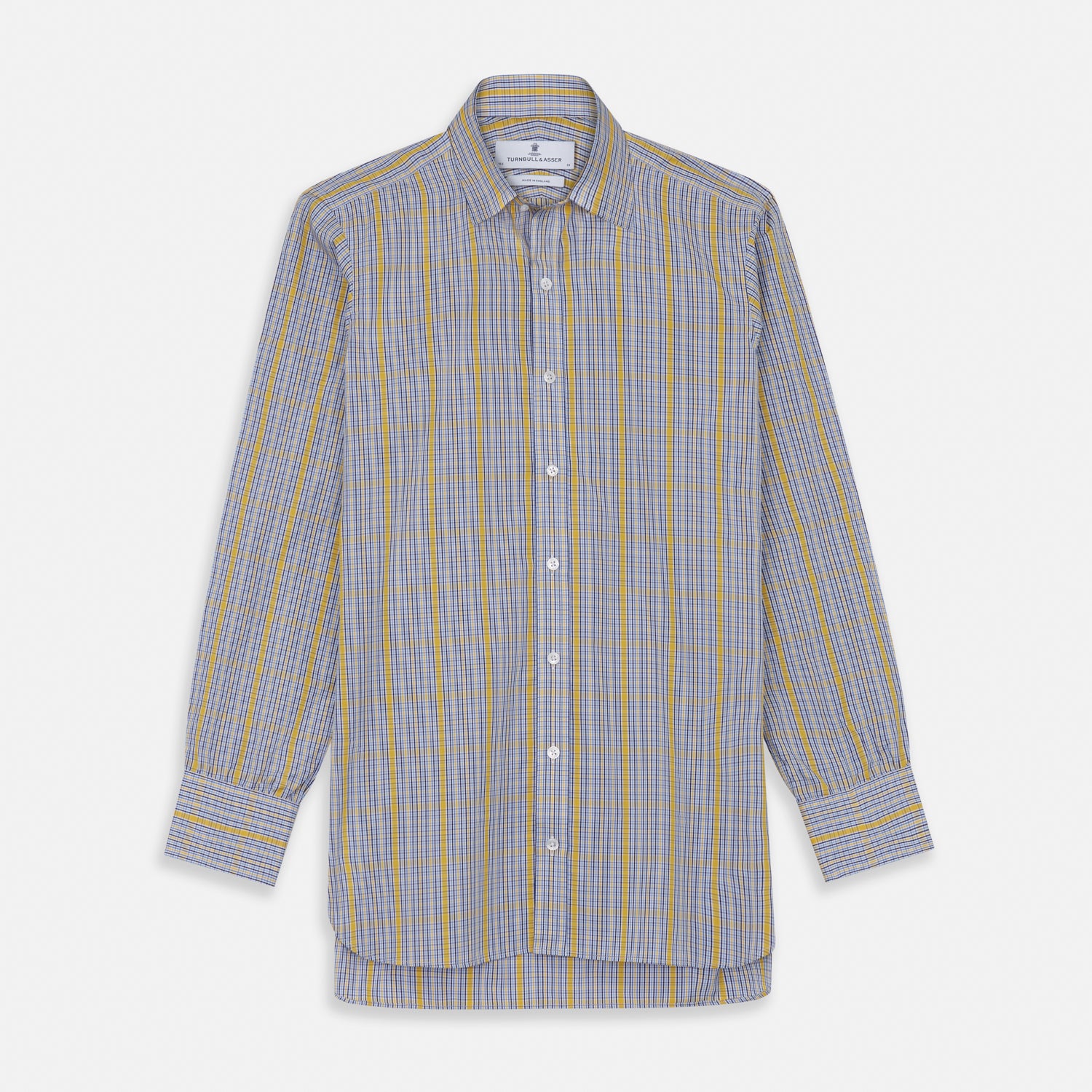 View 2 of product A man stands against a light background, wearing a Turnbull & Asser Yellow and Blue Fancy Check Regular Fit Shirt with T&A Collar, a patterned tie, dark dress pants, and black shoes. He faces forward with hands in pockets and a neutral expression.