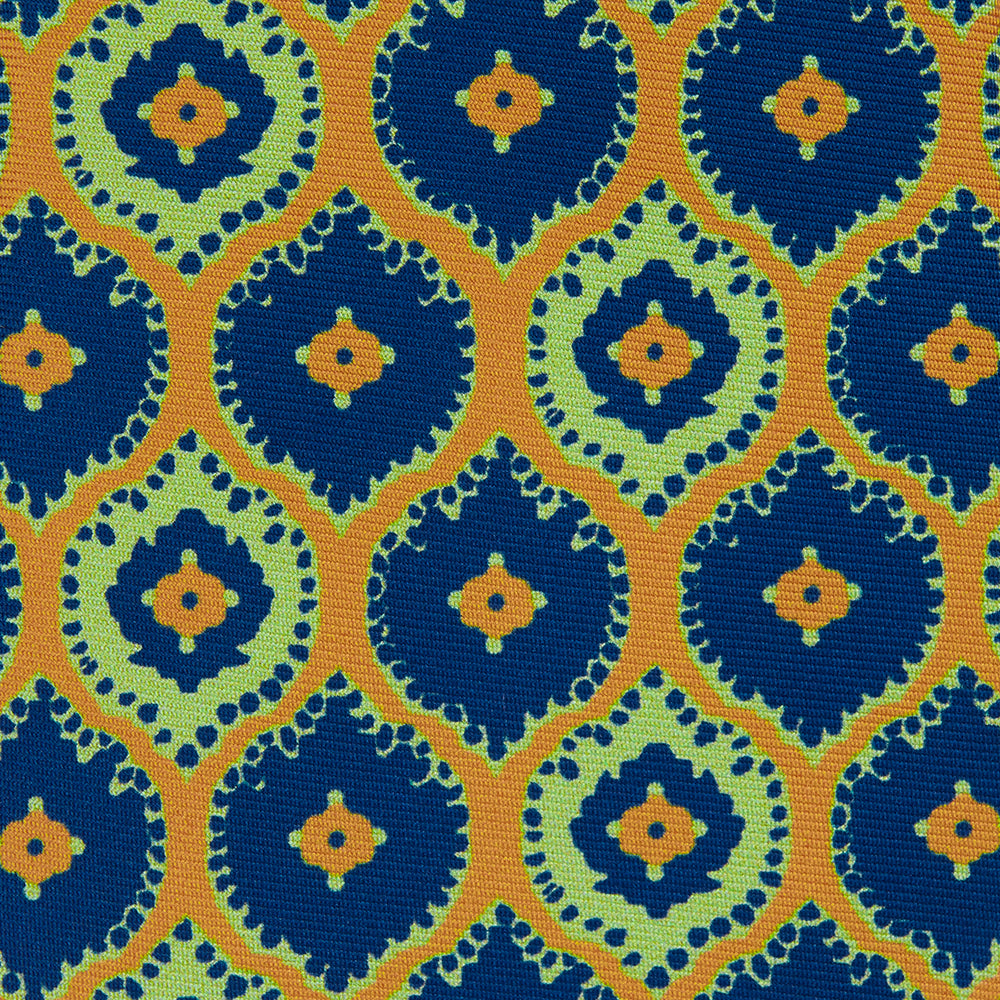 The Yellow Medallion Printed Silk Tie by Turnbull & Asser features a bold abstract medallion pattern in blue, green, and orange on yellow silk, displayed rolled up against a plain white background.