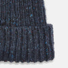 View 2 of product The Turnbull & Asser Navy Donegal Ribbed Merino Hat features thick ribbed knitting, a folded brim, and subtle lighter blue and red flecks throughout the merino yarn, shown against a plain white background.