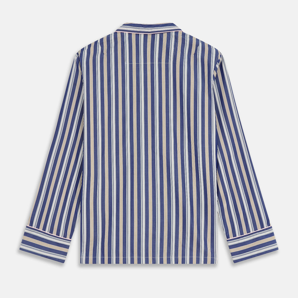 A person stands barefoot on a gray floor in the Turnbull & Asser Blue Multi Stripe Harriet Women’s Pyjama Set with a dark sweater over their shoulders—premium cotton pyjamas that make a perfect gift for her—against a plain beige background.