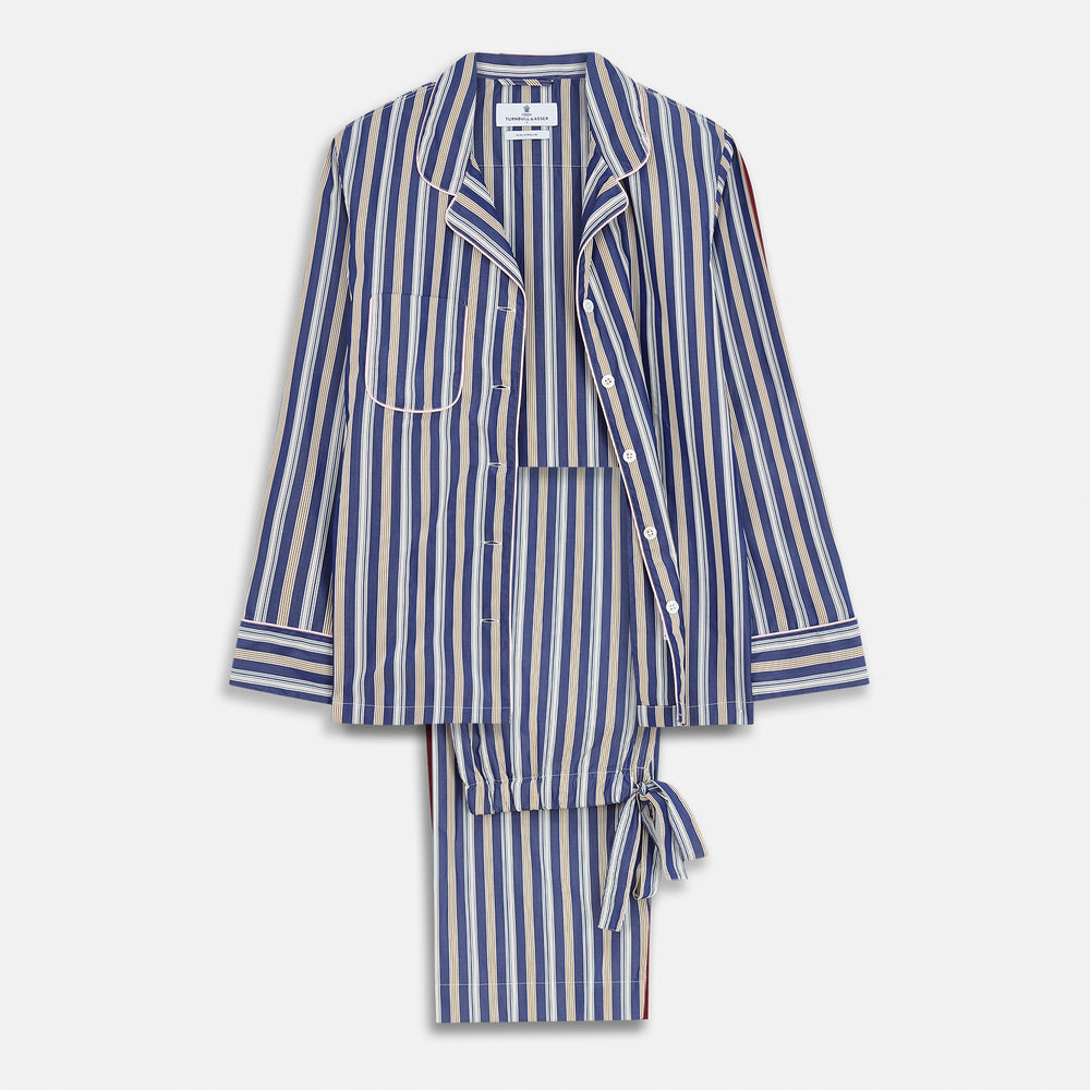 A person stands barefoot on a gray floor in the Turnbull & Asser Blue Multi Stripe Harriet Women’s Pyjama Set with a dark sweater over their shoulders—premium cotton pyjamas that make a perfect gift for her—against a plain beige background.