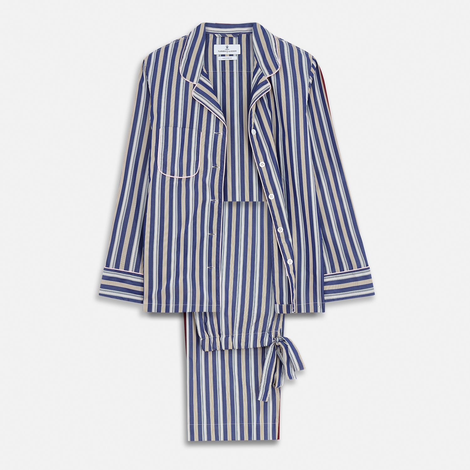 View 2 of product A person stands barefoot on a gray floor in the Turnbull & Asser Blue Multi Stripe Harriet Women’s Pyjama Set with a dark sweater over their shoulders—premium cotton pyjamas that make a perfect gift for her—against a plain beige background.