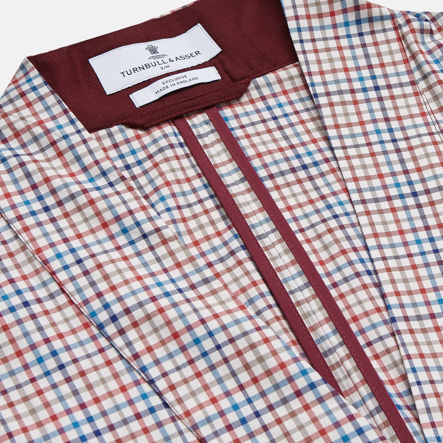 View 2 of product The Turnbull & Asser Burgundy Multi Check Cotton Kimono Gown is a knee-length robe with a burgundy check, red/blue/white pattern, long sleeves, a belt, and a solid burgundy inside collar.