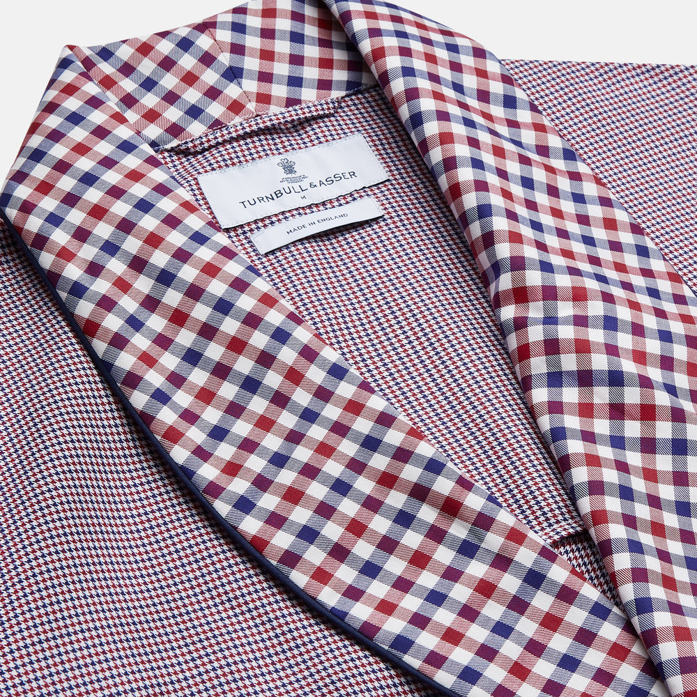 The Turnbull & Asser Burgundy Multi Check Contrast Cotton Gown features a long silhouette with a shawl collar, waist tie, and three pockets, accented by red, black, and white checkered trim—ideal for luxurious nights at home.