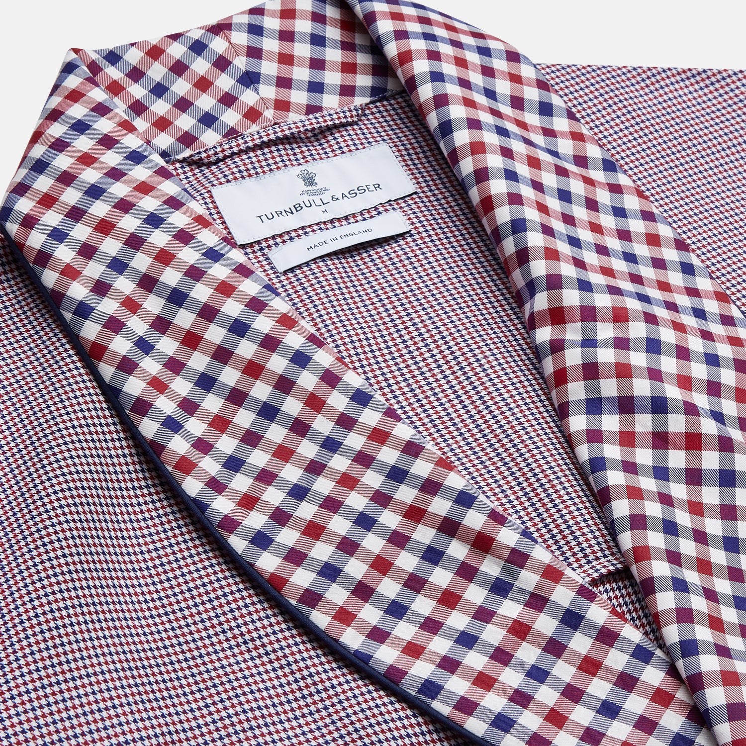 View 2 of product The Turnbull & Asser Burgundy Multi Check Contrast Cotton Gown features a long silhouette with a shawl collar, waist tie, and three pockets, accented by red, black, and white checkered trim—ideal for luxurious nights at home.