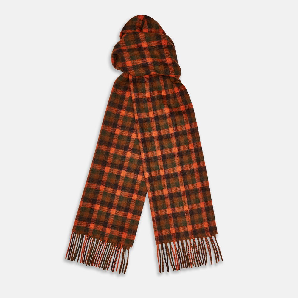 A man stands against a beige background wearing a navy long-sleeve shirt, brown pants, and a Turnbull & Asser Orange Multi Shepherd Check Cashmere Scarf draped around his neck. He faces forward with a neutral expression.