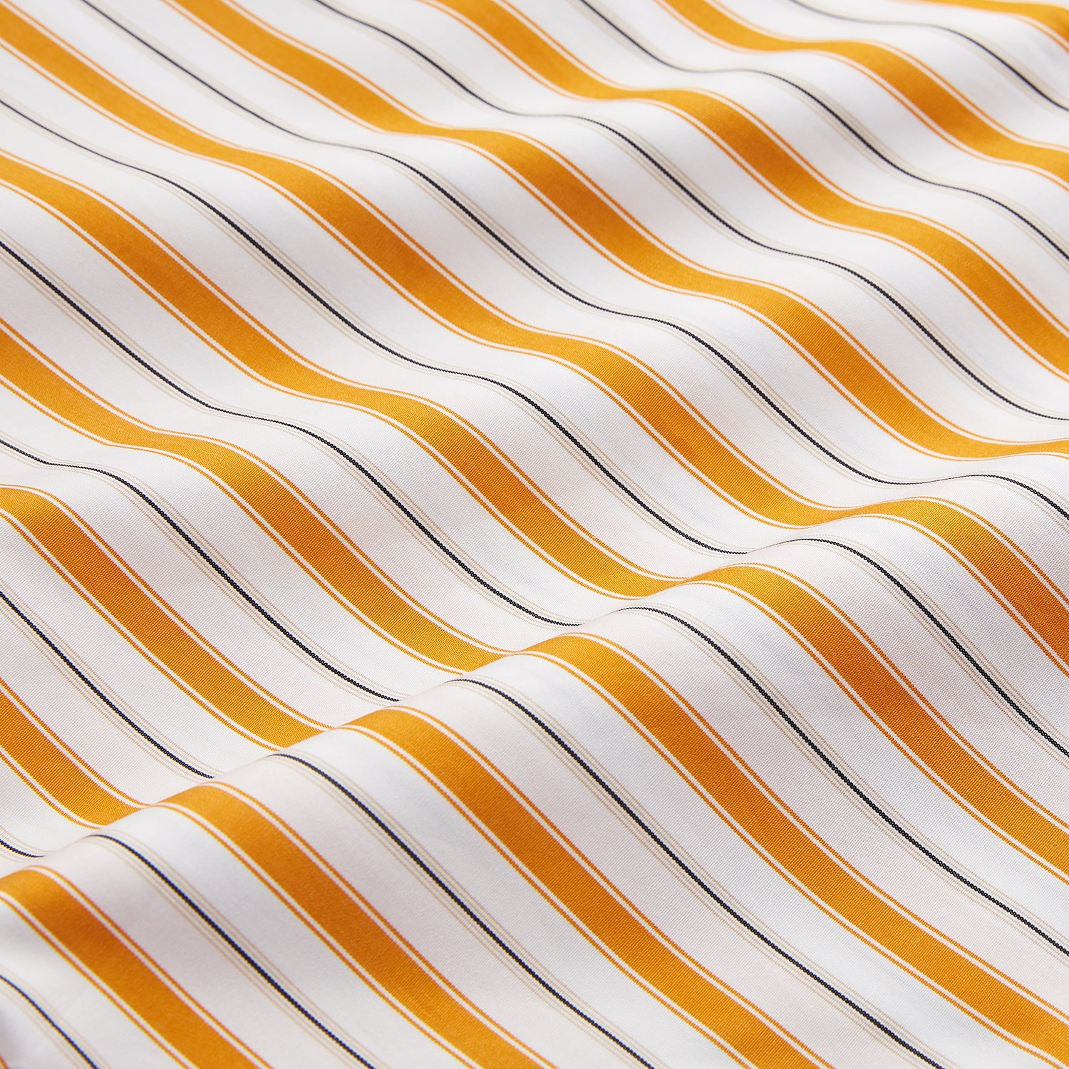 View 6 of product A man stands against a tan background wearing a Turnbull & Asser Orange Multi Stripe Regular Fit Shirt with T&A Collar and 3 Button Cuffs, paired with tan dress pants, brown belt, and brown shoes. He faces forward with a neutral expression.