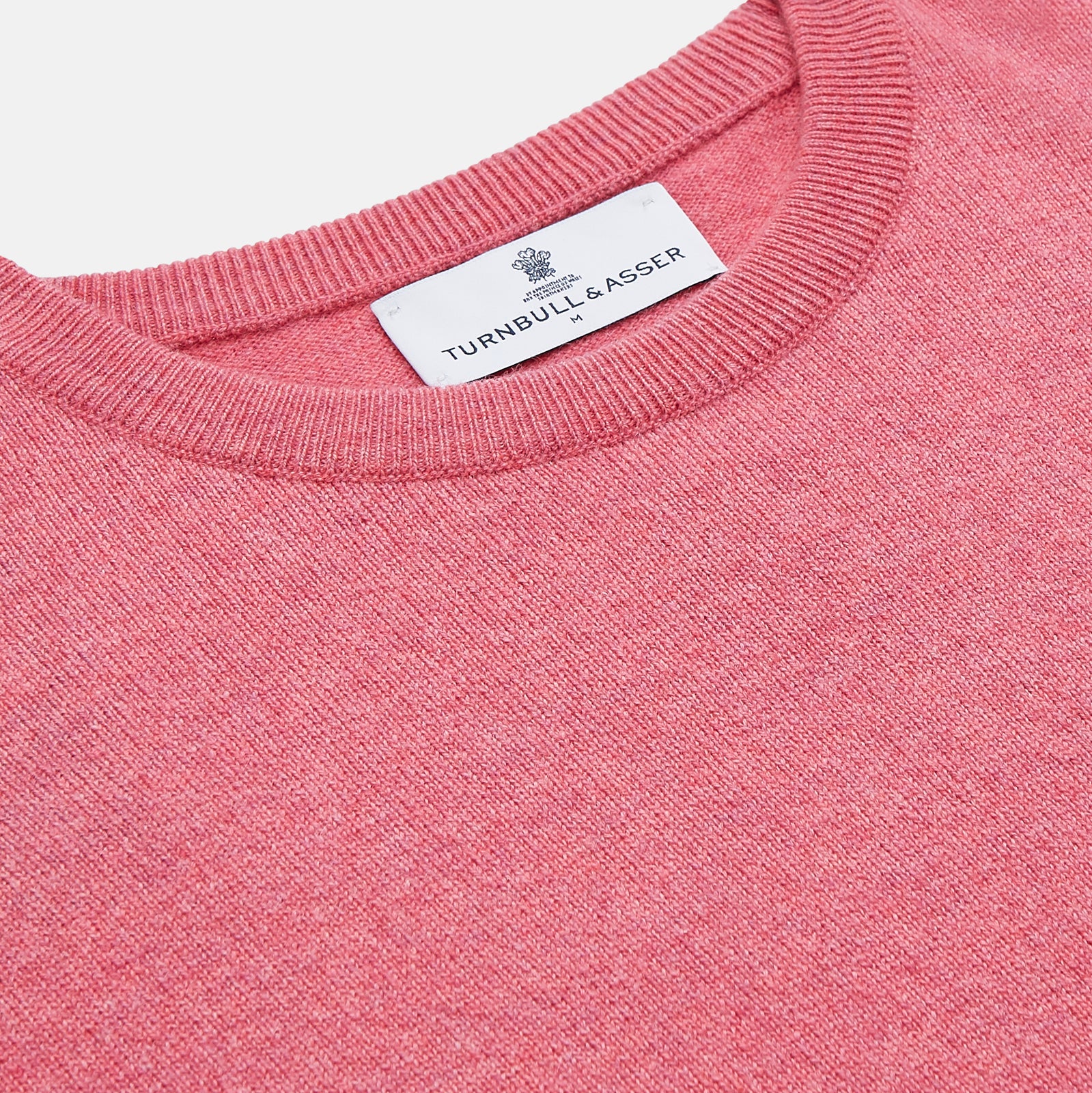 View 2 of product The Turnbull & Asser Pink Cashmere Glenn Jumper is a solid pink, long-sleeved menswear sweater with a crewneck, shown laid flat on a white background.