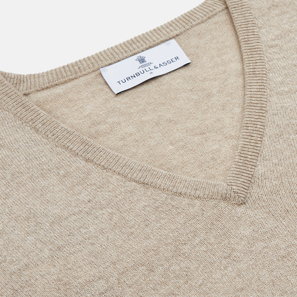 The Turnbull & Asser Beige Cashmere Paden V-Neck Jumper is laid flat on a white background. Knitted in Scotland, this men's staple features ribbed cuffs, hem, and neckline with a soft, smooth texture.