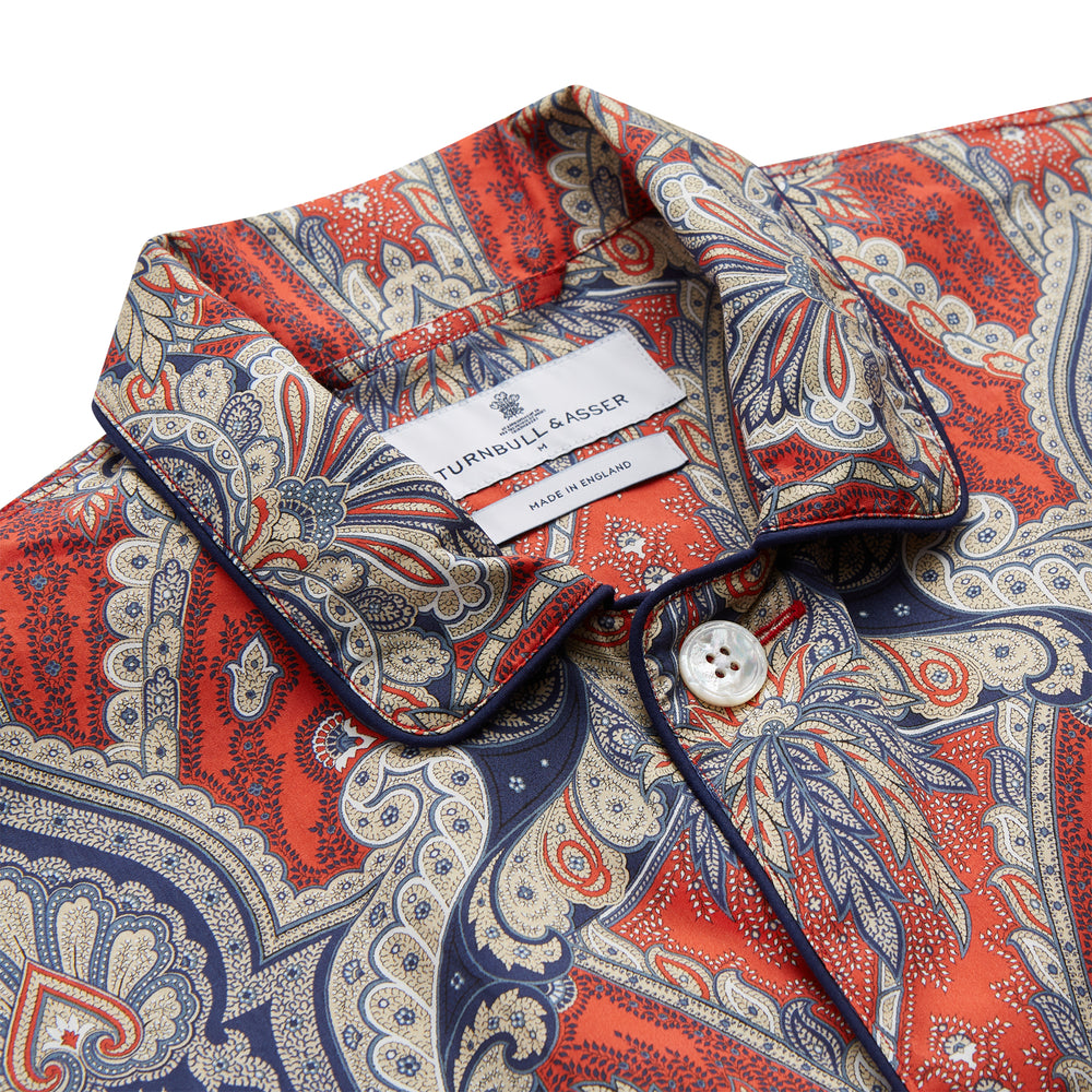 The Turnbull & Asser Red Baroque Silk-Blend Hyde Pyjama Set features a long-sleeve button-up shirt and matching pants in an intricate red, blue, and beige floral-geometric print, displayed flat against a white background.