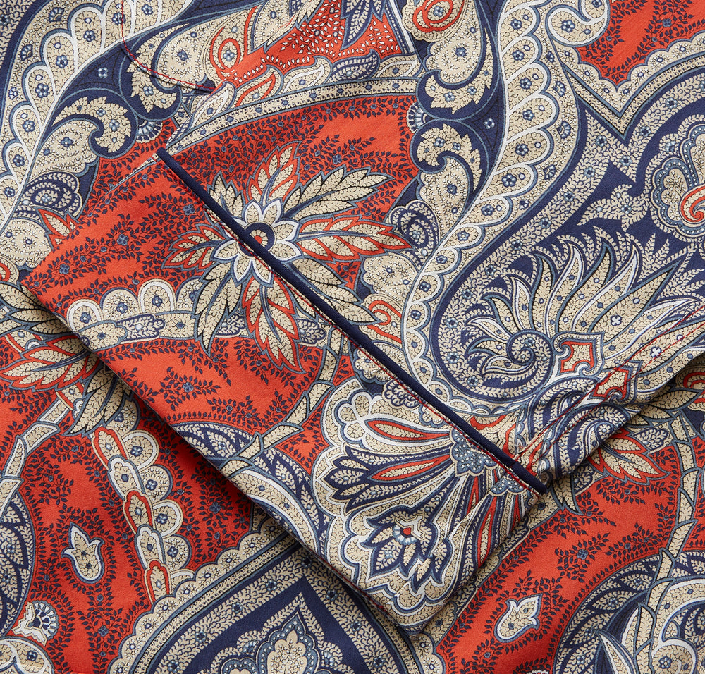 The Turnbull & Asser Red Baroque Silk-Blend Hyde Pyjama Set features a long-sleeve button-up shirt and matching pants in an intricate red, blue, and beige floral-geometric print, displayed flat against a white background.