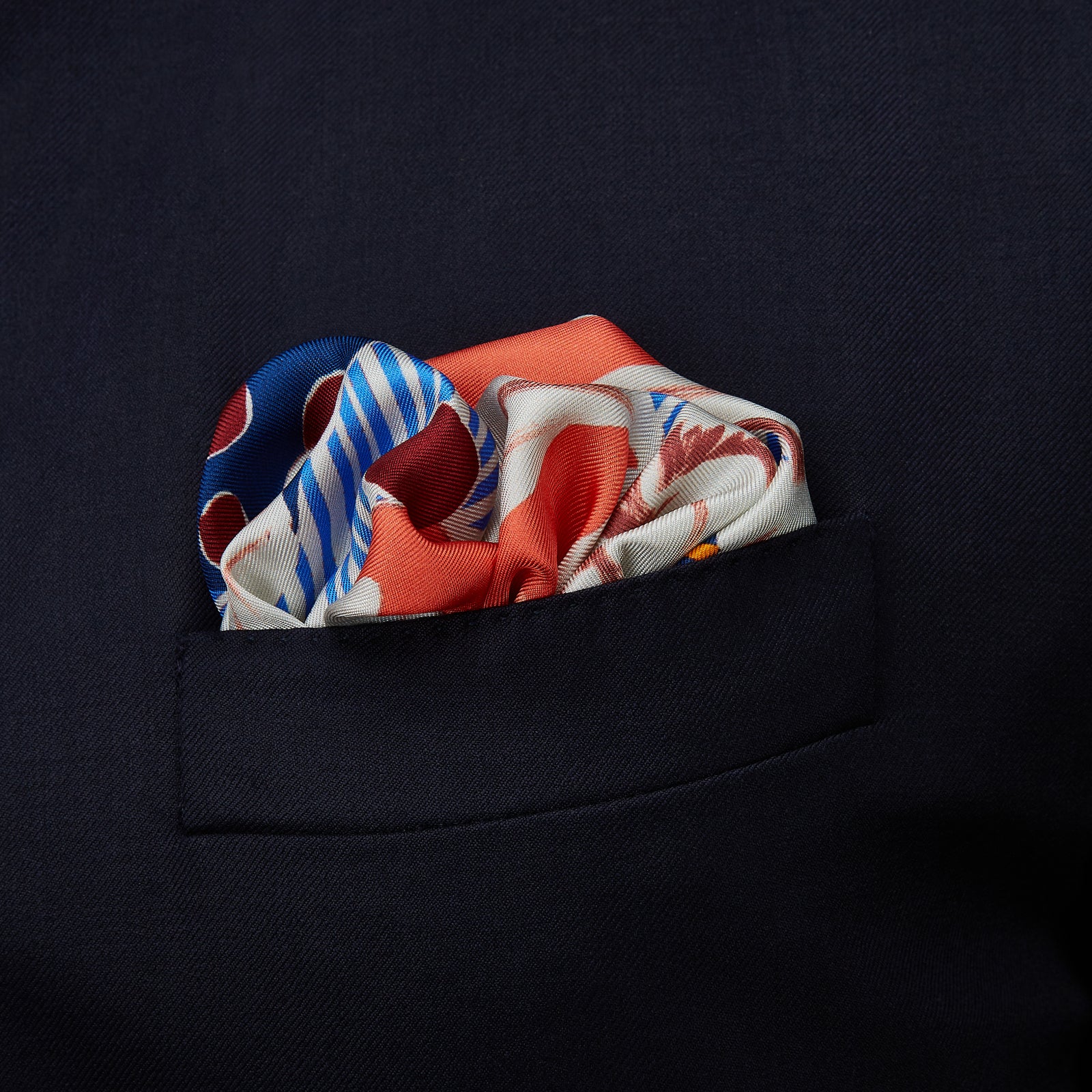 View 2 of product The Pink and Red Lily Silk Pocket Square by Turnbull & Asser features a vibrant, hand-drawn floral design with large lilies and abstract shapes in pink, white, blue, and yellow on pale blue vertical stripes.