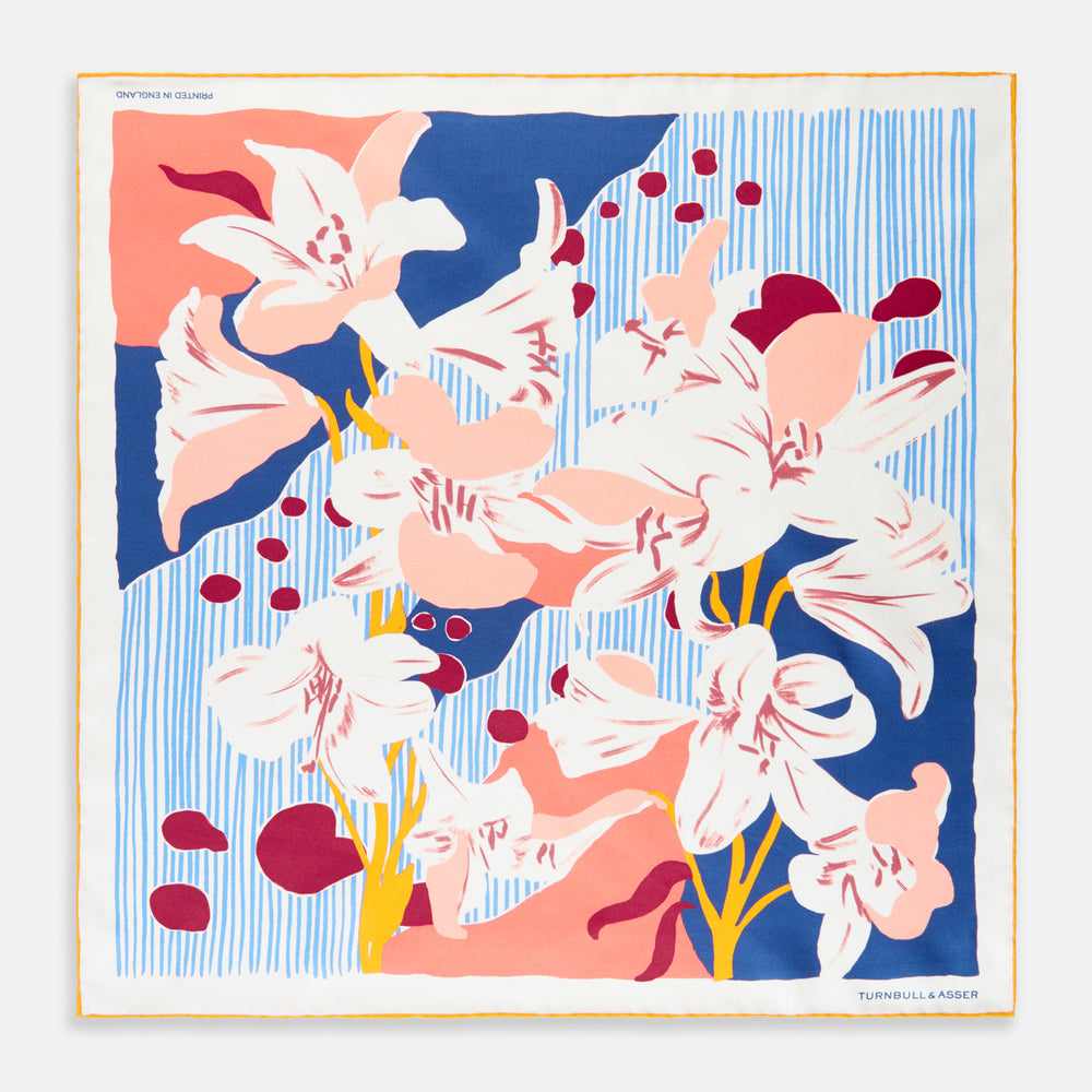 The Pink and Red Lily Silk Pocket Square by Turnbull & Asser features a vibrant, hand-drawn floral design with large lilies and abstract shapes in pink, white, blue, and yellow on pale blue vertical stripes.