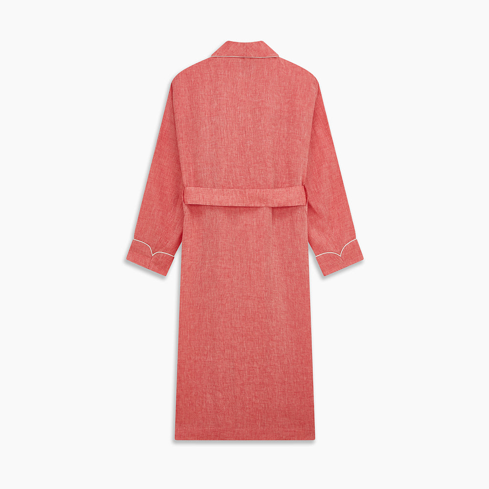 The Pink Linen Arnold Gown by Turnbull & Asser features white piping, long sleeves, a shawl collar, chest pocket, and a wrap-around belt tied at the waist, shown on a white background.