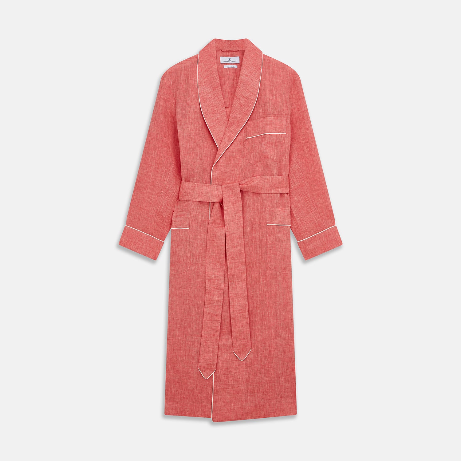 View 1 of product The Pink Linen Arnold Gown by Turnbull & Asser features white piping, long sleeves, a shawl collar, chest pocket, and a wrap-around belt tied at the waist, shown on a white background.