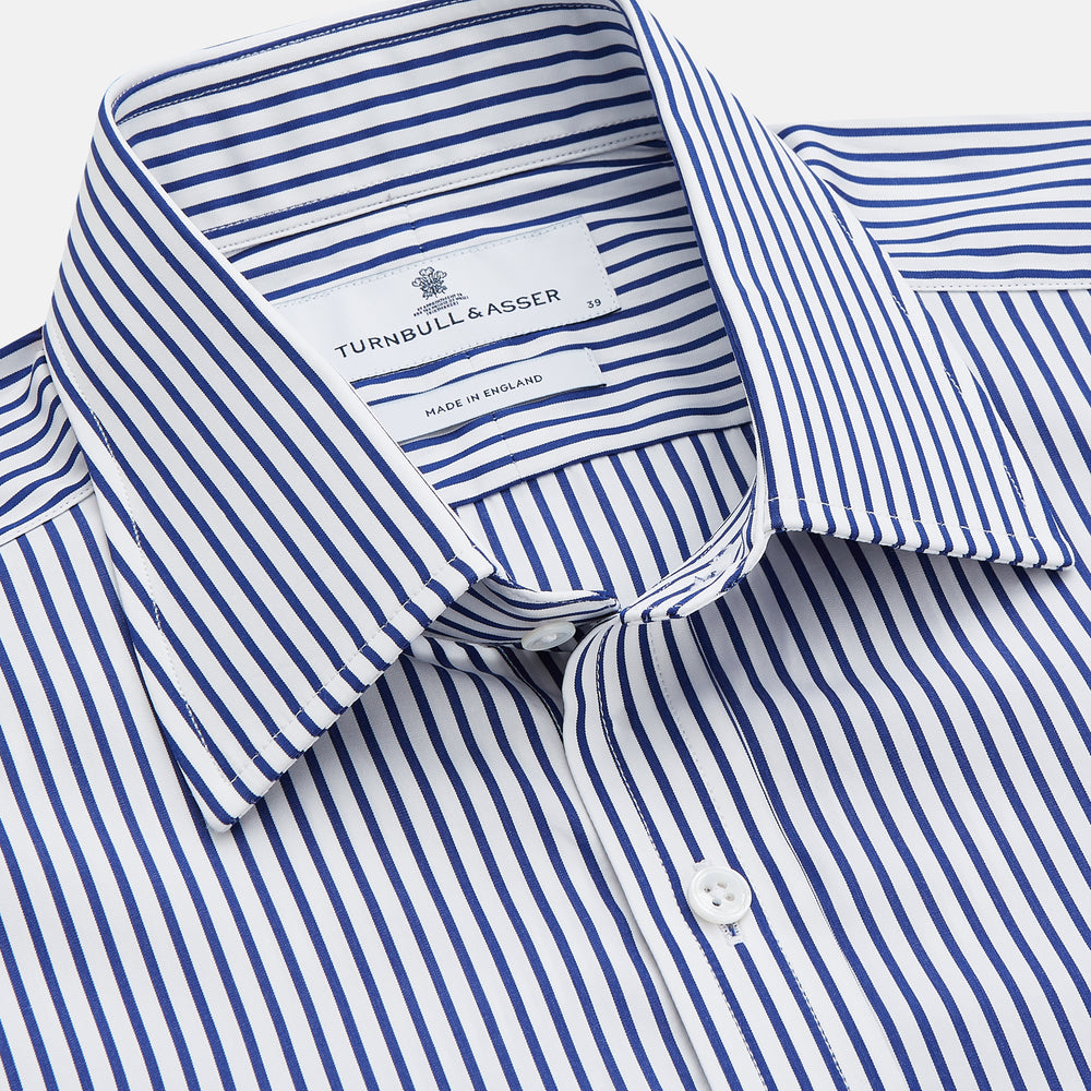 The Turnbull & Asser Navy Stripe Cotton Regular Fit Whitby Shirt features vertical blue and white stripes, long sleeves, a collar, double cuffs, and a button-down front, shown laid flat on a white background.