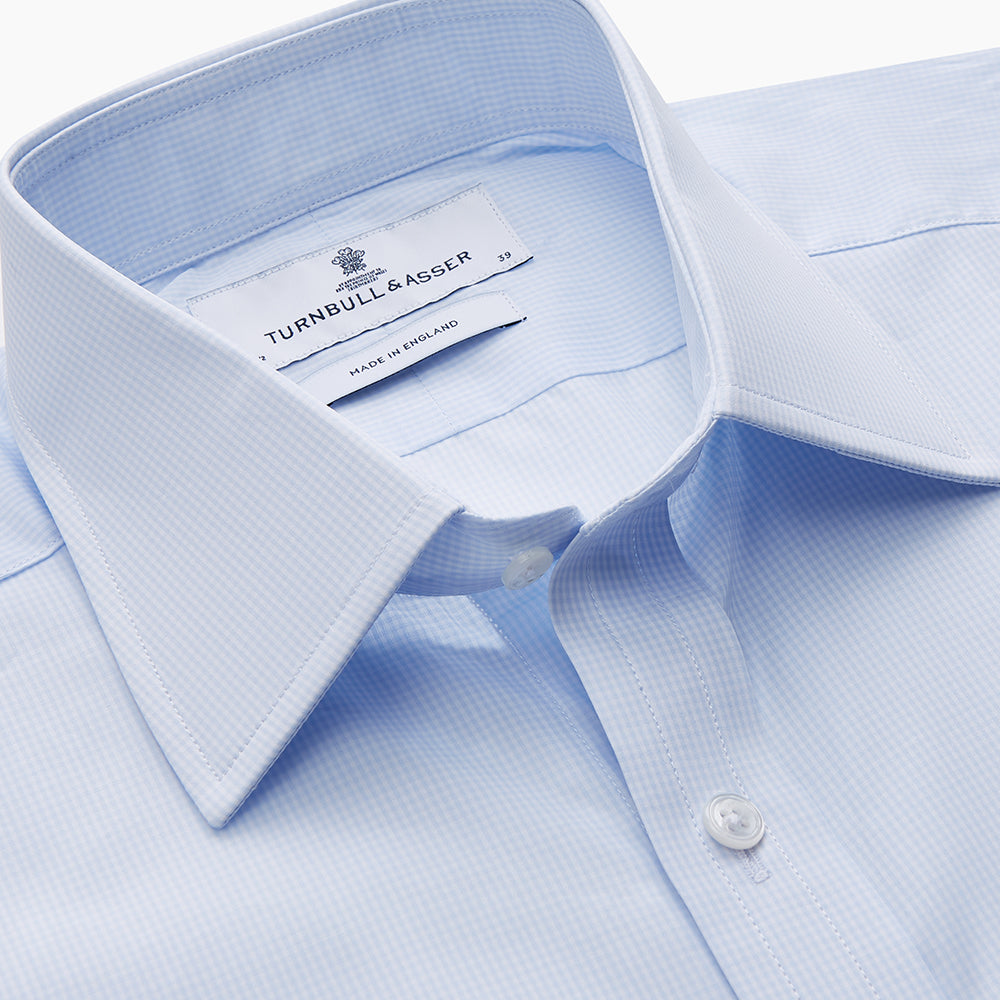 The Light Blue Multi-Check Cotton Regular Fit Mayfair Shirt by Turnbull & Asser is shown laid flat, featuring a classic T&A collar, front buttons, and buttoned cuffs on a white background.