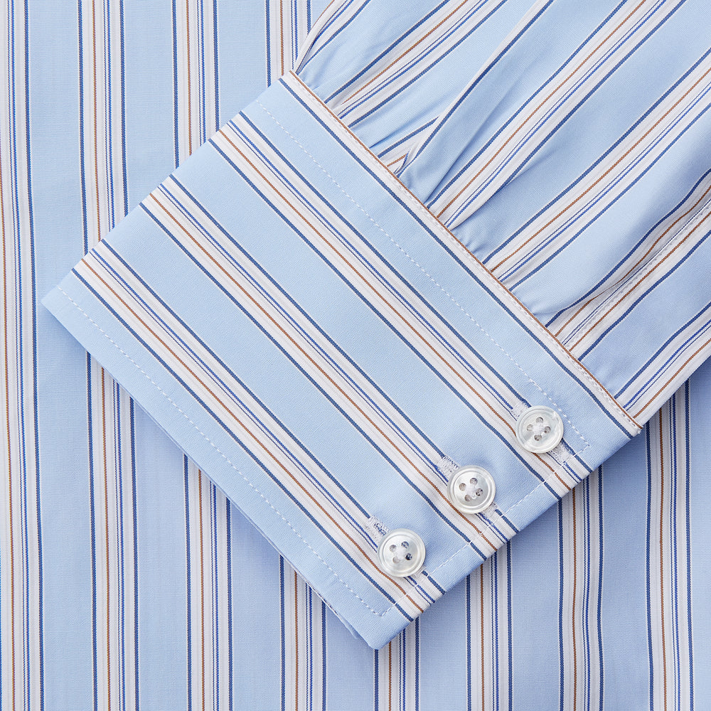 The Turnbull & Asser Pale Blue Multi-stripe Cotton Regular Fit Mayfair Shirt, featuring long sleeves, buttoned cuffs, and a signature T&A collar, is laid flat on a white background.