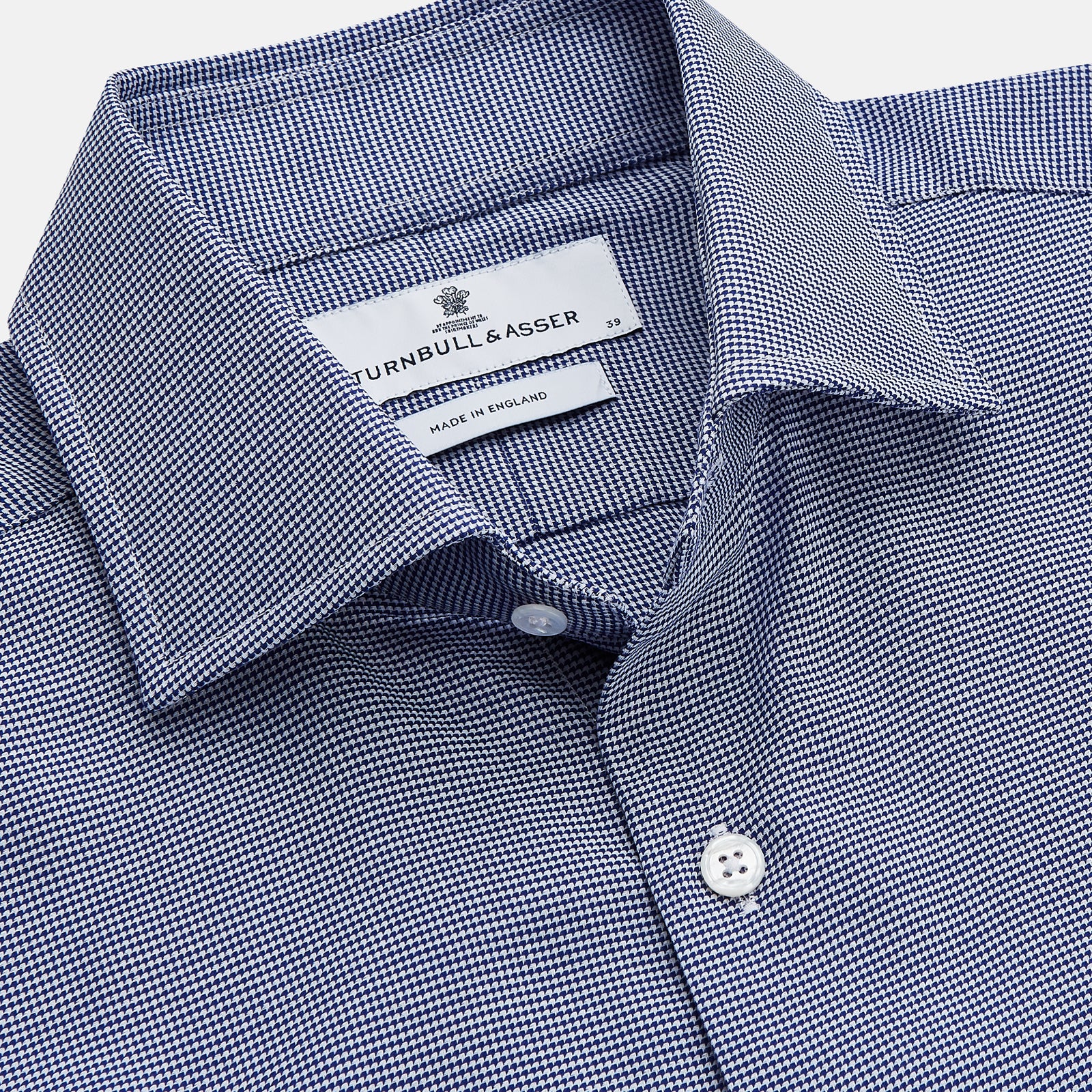View 2 of product The Turnbull & Asser Navy Pattern Cotton Voile Tailored Fit Shelton Shirt is laid flat, showcasing its classic collar and white front and cuff buttons.