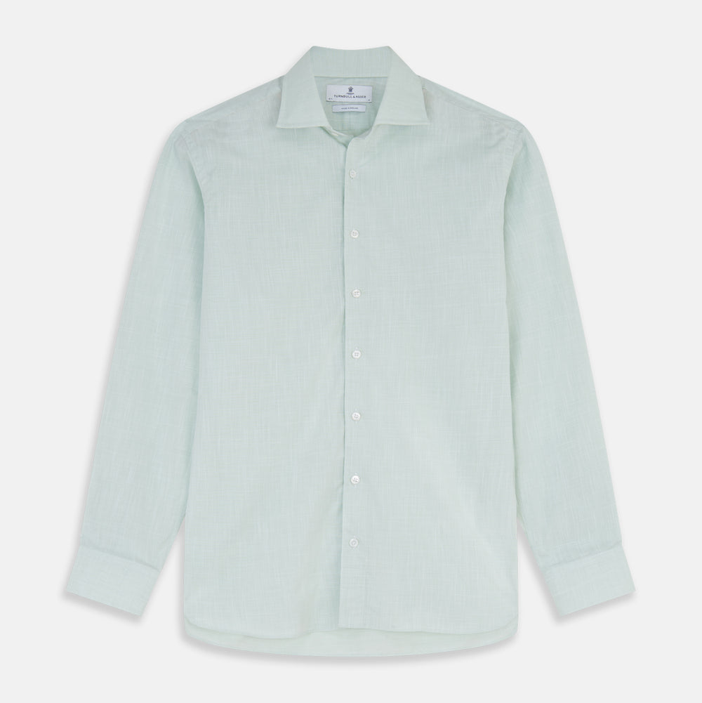 The Turnbull & Asser Light Green Chambray Tailored Fit Shelton Shirt features long sleeves, a classic collar, and white buttons—an elegant men's formal shirt shown neatly laid flat on a white background.