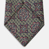 View 4 of product The Green Floral Tile Silk Tie by Turnbull & Asser features a gold background with a repeating green floral pattern in red, navy blue, and cream, showcasing classic style and an evenly distributed silk texture throughout.