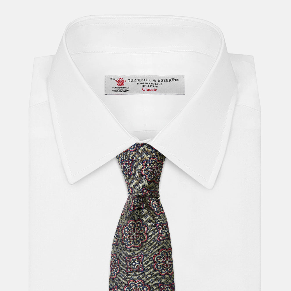 The Green Floral Tile Silk Tie by Turnbull & Asser features a gold background with a repeating green floral pattern in red, navy blue, and cream, showcasing classic style and an evenly distributed silk texture throughout.