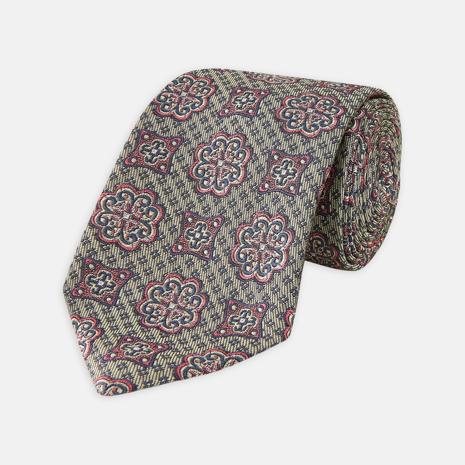 View 1 of product The Green Floral Tile Silk Tie by Turnbull & Asser features a gold background with a repeating green floral pattern in red, navy blue, and cream, showcasing classic style and an evenly distributed silk texture throughout.