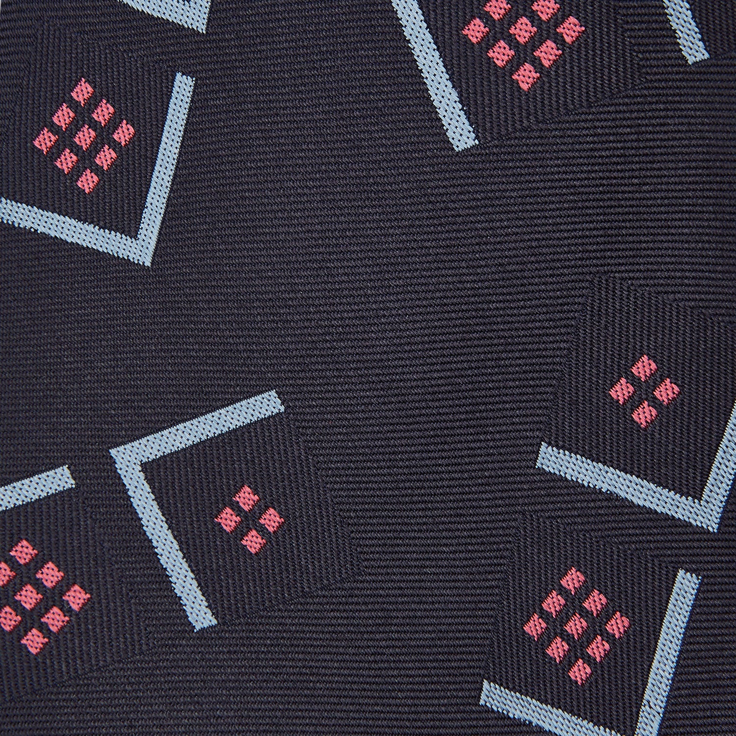 View 2 of product A Turnbull & Asser Navy Graphic Deco Silk Tie, featuring light blue chevrons and red squares on a dark navy background, shown rolled up against a plain white backdrop.