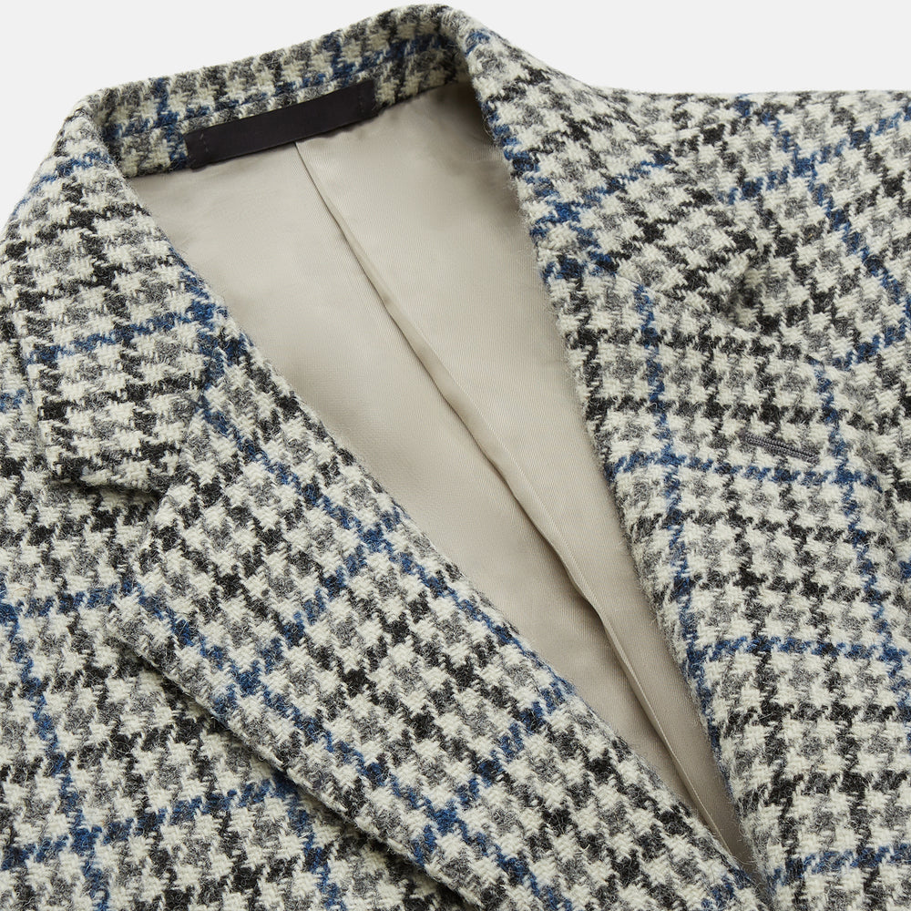 The Grey and Navy Tweed Barrington Blazer by Turnbull & Asser is a single-breasted jacket with notched lapels, two front buttons, flap pockets, and a tailored fit—expertly made in Italy for sophisticated style.
