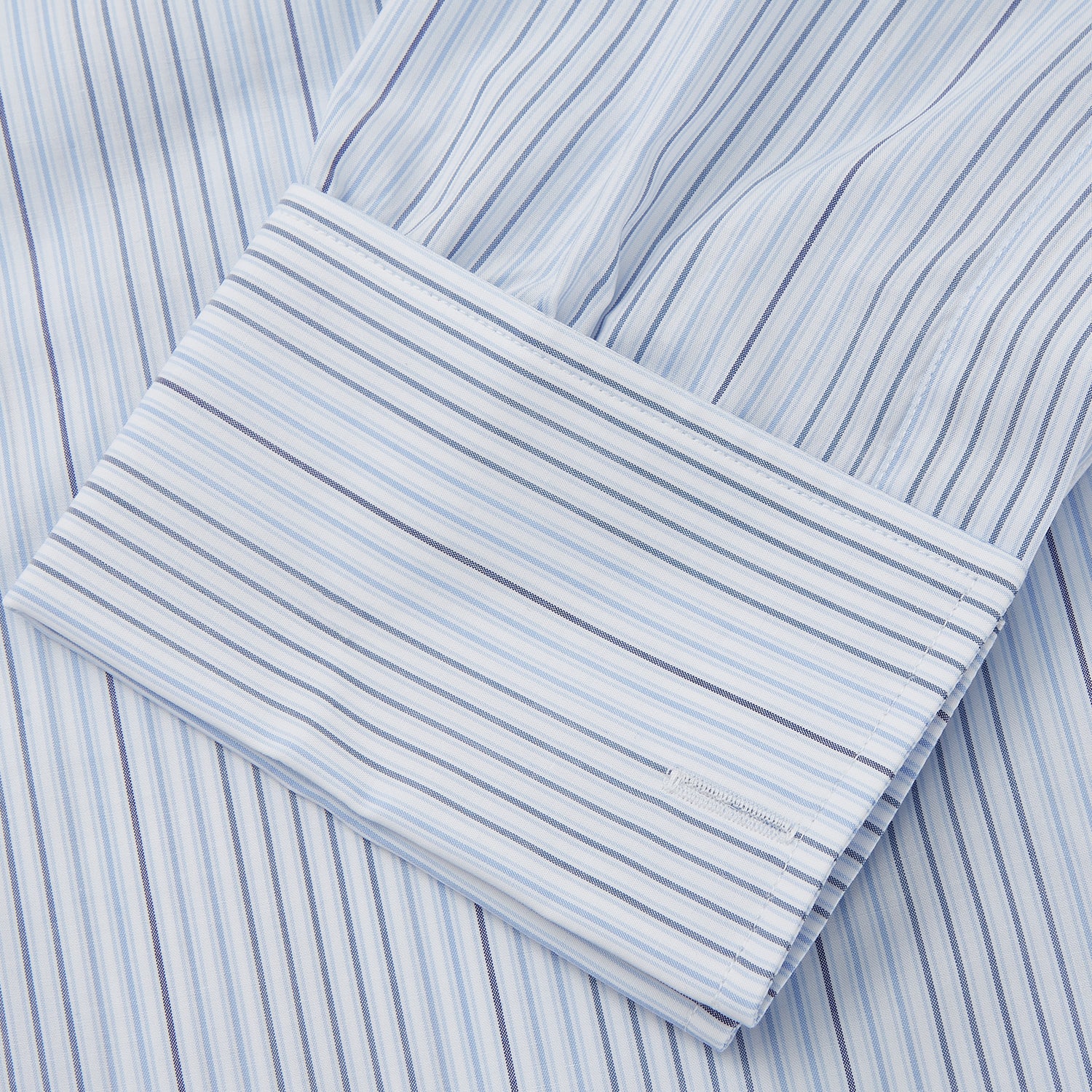 View 3 of product Turnbull & Asser’s Blue and White Stripe Twill Cotton Regular Fit Shirt features a T&A collar, double cuffs, and classic stripes, shown laid flat on a white background.
