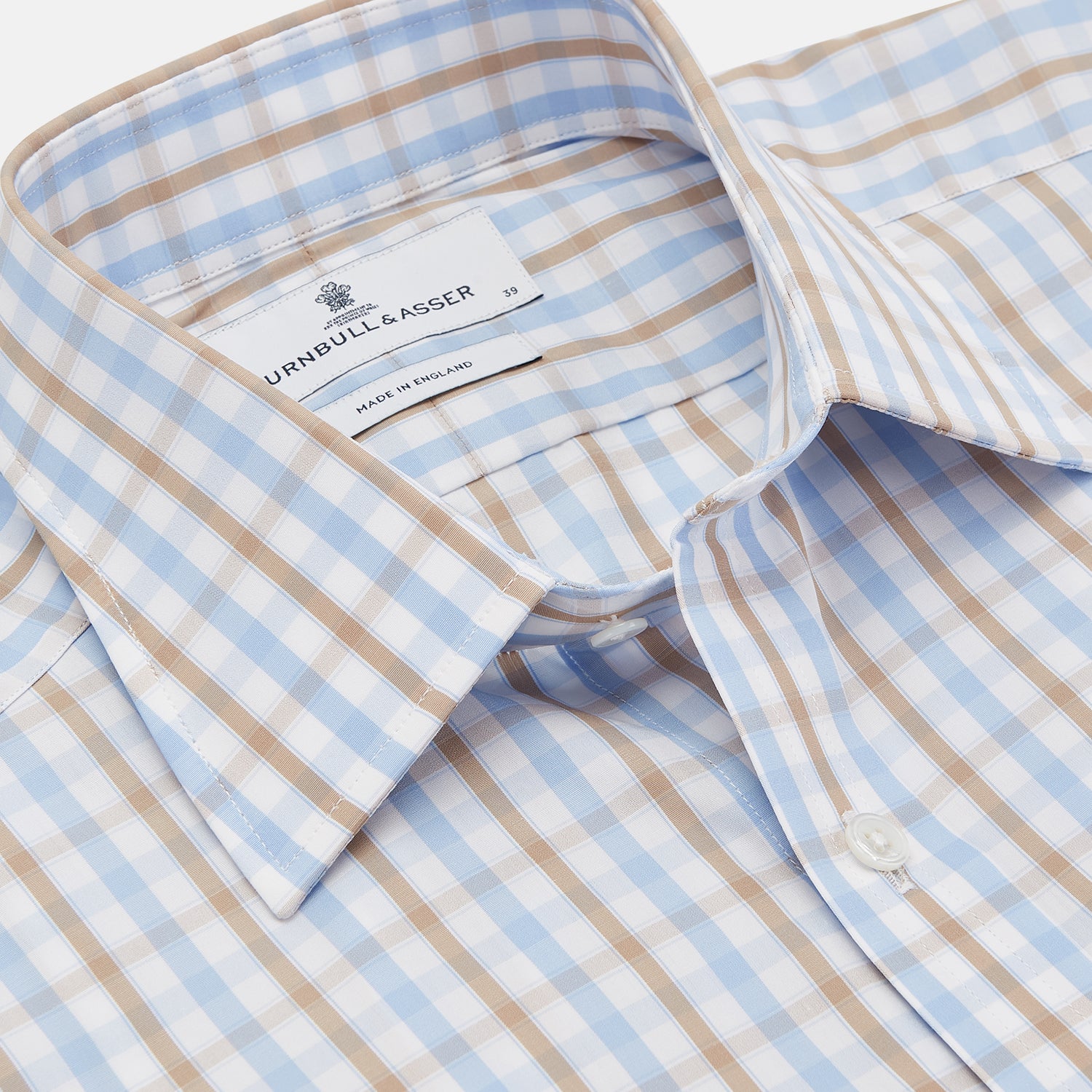 View 2 of product The Turnbull & Asser Blue and Brown Check Poplin Shirt features a T&A collar, 3-button cuffs, and a regular fit cotton construction, shown laid flat against a white background.