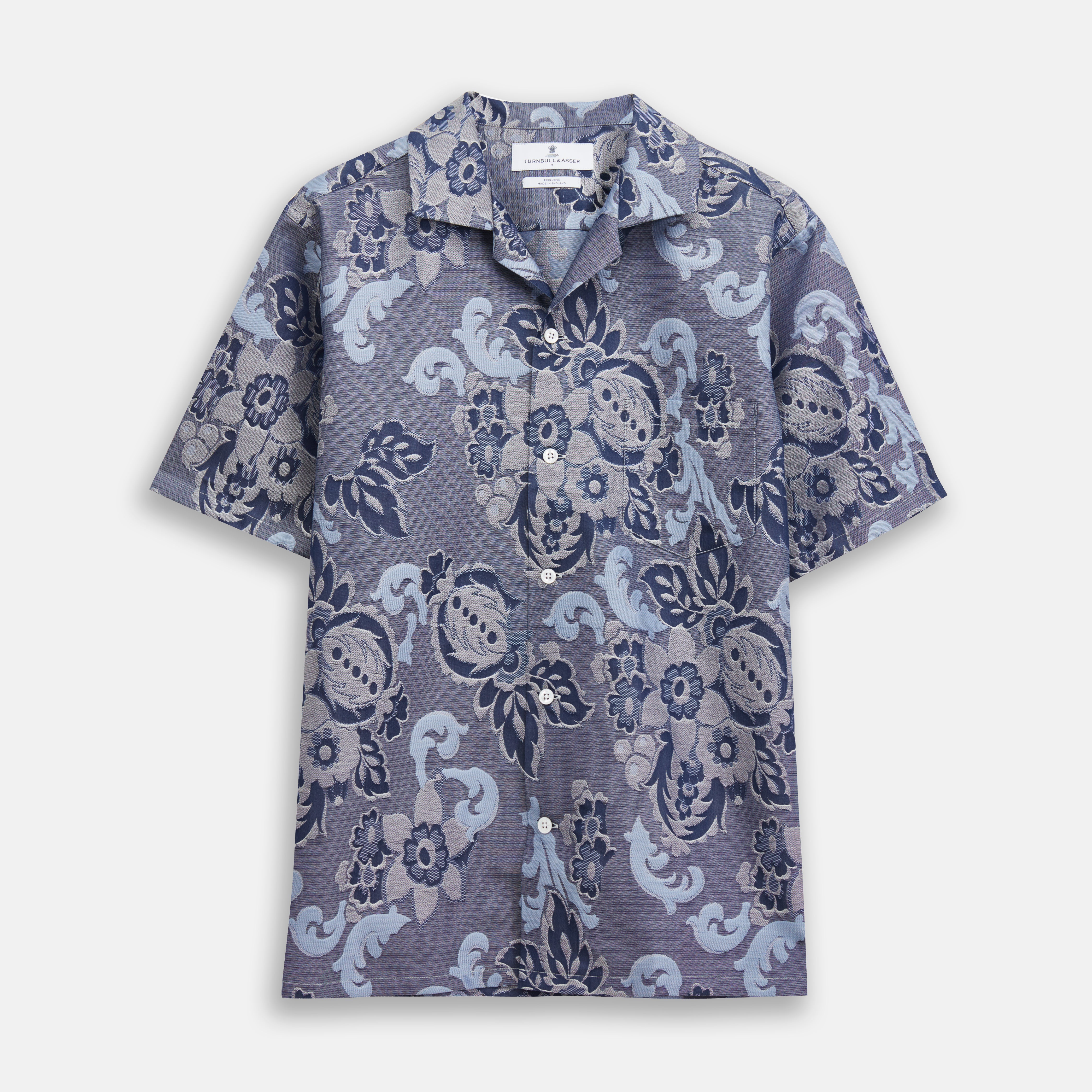 View 1 of product The Blue & White Tapestry Weave Cotton Holiday Fit Shirt by Turnbull & Asser features short sleeves, a revere collar, and a button-up front with a blue and white patterned textured fabric, shown against a plain white background.