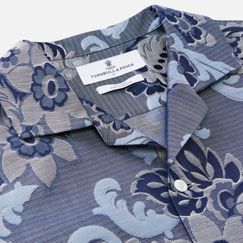 The Blue & White Tapestry Weave Cotton Holiday Fit Shirt by Turnbull & Asser features short sleeves, a revere collar, and a button-up front with a blue and white patterned textured fabric, shown against a plain white background.