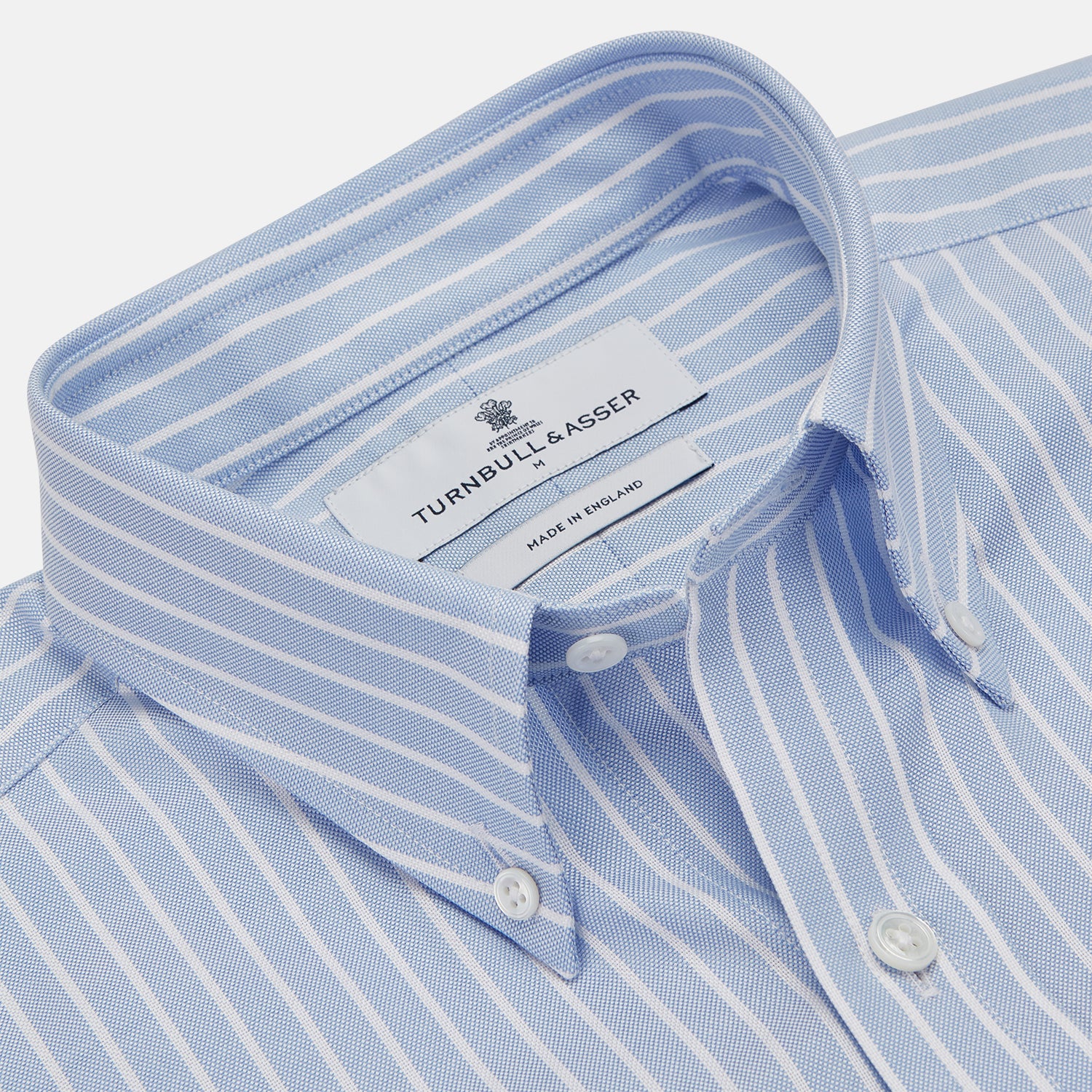 View 2 of product The Turnbull & Asser Blue and White Broad Stripe Oxford Weekend Fit Shirt features a Dorset collar, 1-button cuffs, and classic stripes—ideal for smart-casual days. Laid flat on a white background.