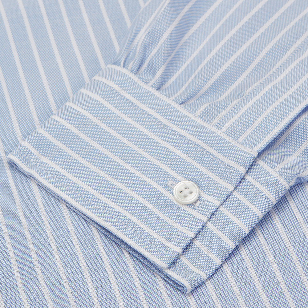 The Turnbull & Asser Blue and White Broad Stripe Oxford Weekend Fit Shirt features a Dorset collar, 1-button cuffs, and classic stripes—ideal for smart-casual days. Laid flat on a white background.