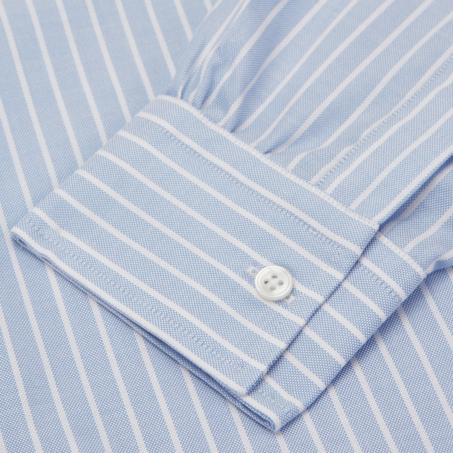 View 3 of product The Turnbull & Asser Blue and White Broad Stripe Oxford Weekend Fit Shirt features a Dorset collar, 1-button cuffs, and classic stripes—ideal for smart-casual days. Laid flat on a white background.