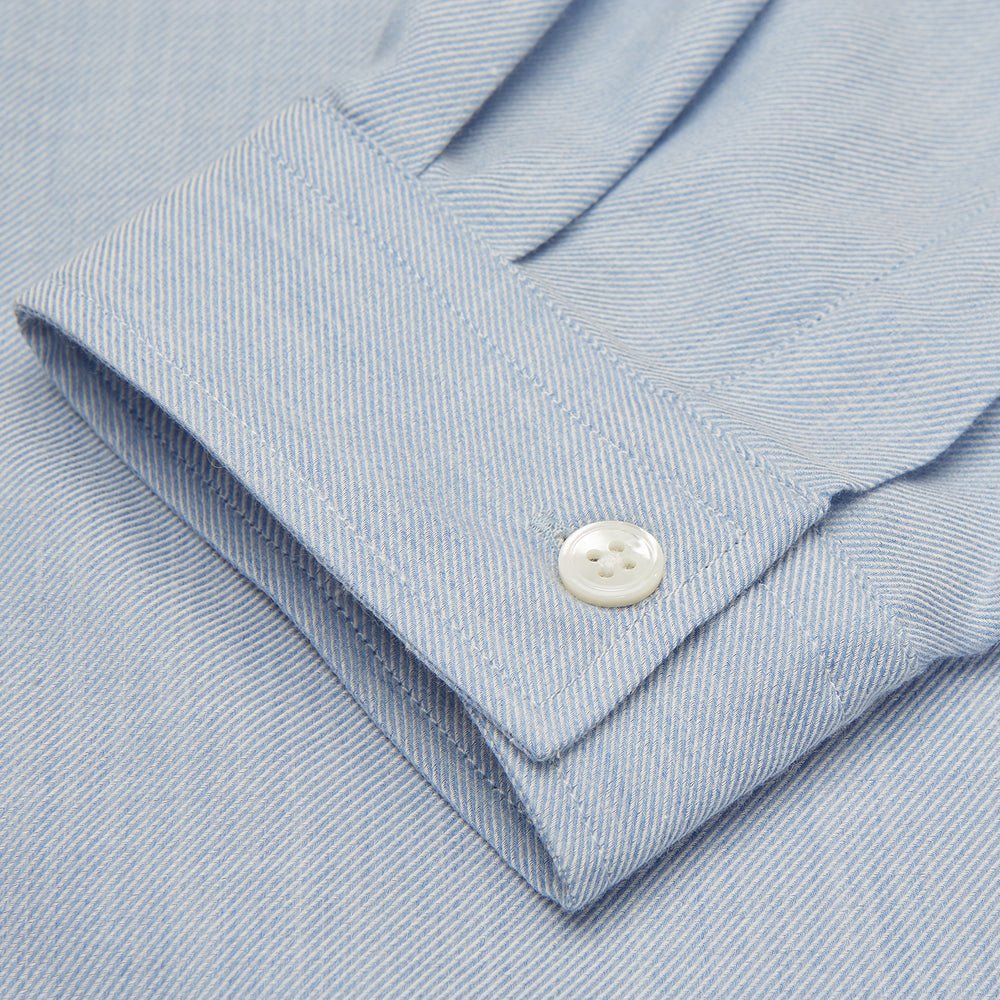 The Turnbull & Asser Holiday Fit Blue Cotton and Cashmere Blend Shirt features long sleeves, a classic collar, single chest pocket, and 1-button cuffs with white buttons, shown laid flat on a white background.