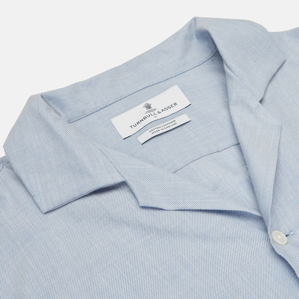 The Turnbull & Asser Holiday Fit Blue Cotton and Cashmere Blend Shirt features long sleeves, a classic collar, single chest pocket, and 1-button cuffs with white buttons, shown laid flat on a white background.