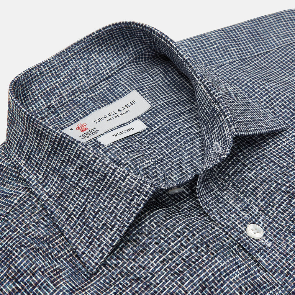 The Turnbull & Asser Weekend Fit Navy Check Linen Shirt features a Derby collar, left chest pocket, 1-button cuffs, and white buttons in textured microcheck fabric, shown laid flat on a white background.