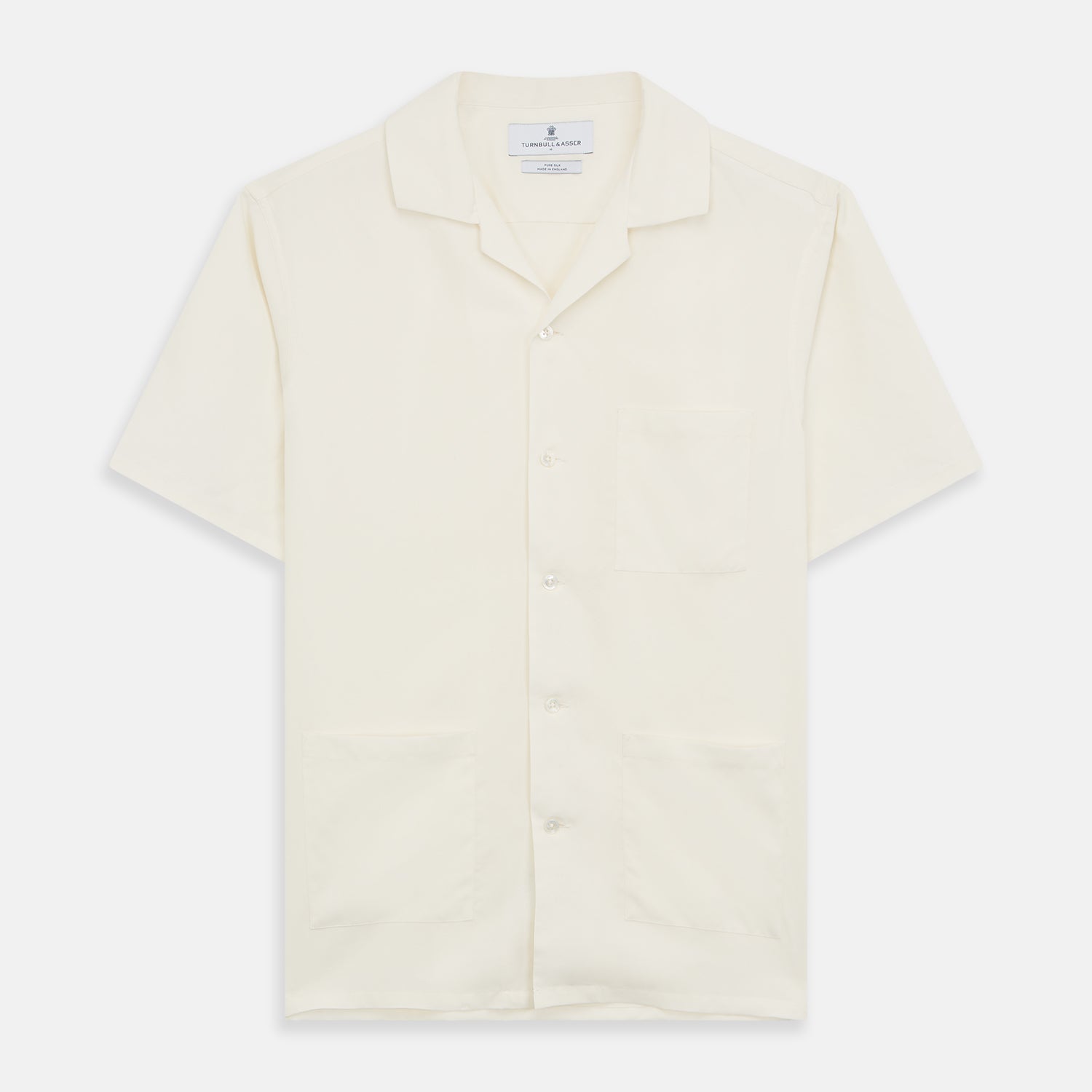 View 1 of product The Turnbull & Asser Cream Holiday Fit Silk Phillips Shirt features a revere collar, short sleeves, and three front pockets, shown flat on a white background.